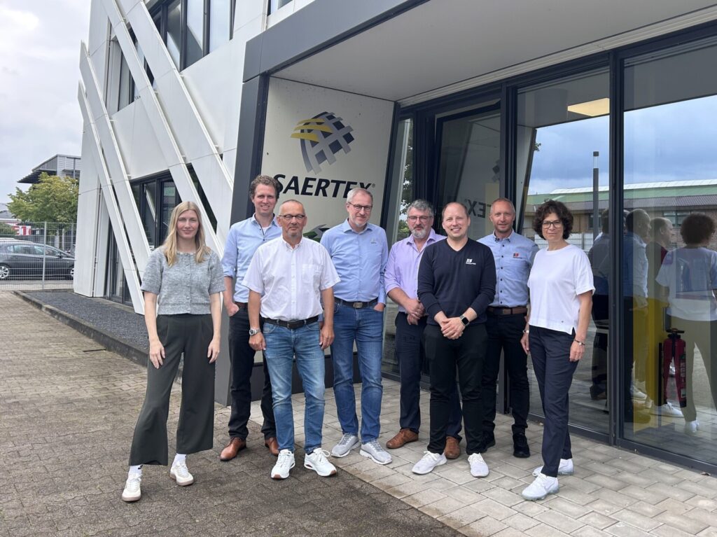 Group of people in front of the Saertex logo in a modern building