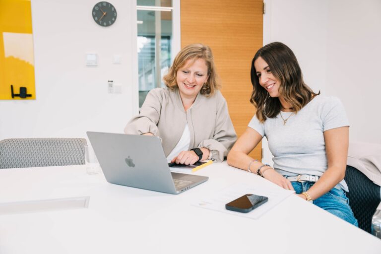Zwei Frauen schauen auf einen Laptop und arbeiten zusammen
