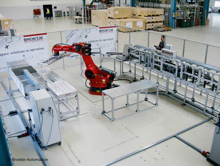 Ein roter Industrieroboter in einer Produktionshalle neben Förderanlagen und technischen Geräten.
