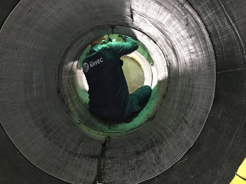 Ein Arbeiter sitzt in einem großen zylindrischen Rohr und arbeitet darin.