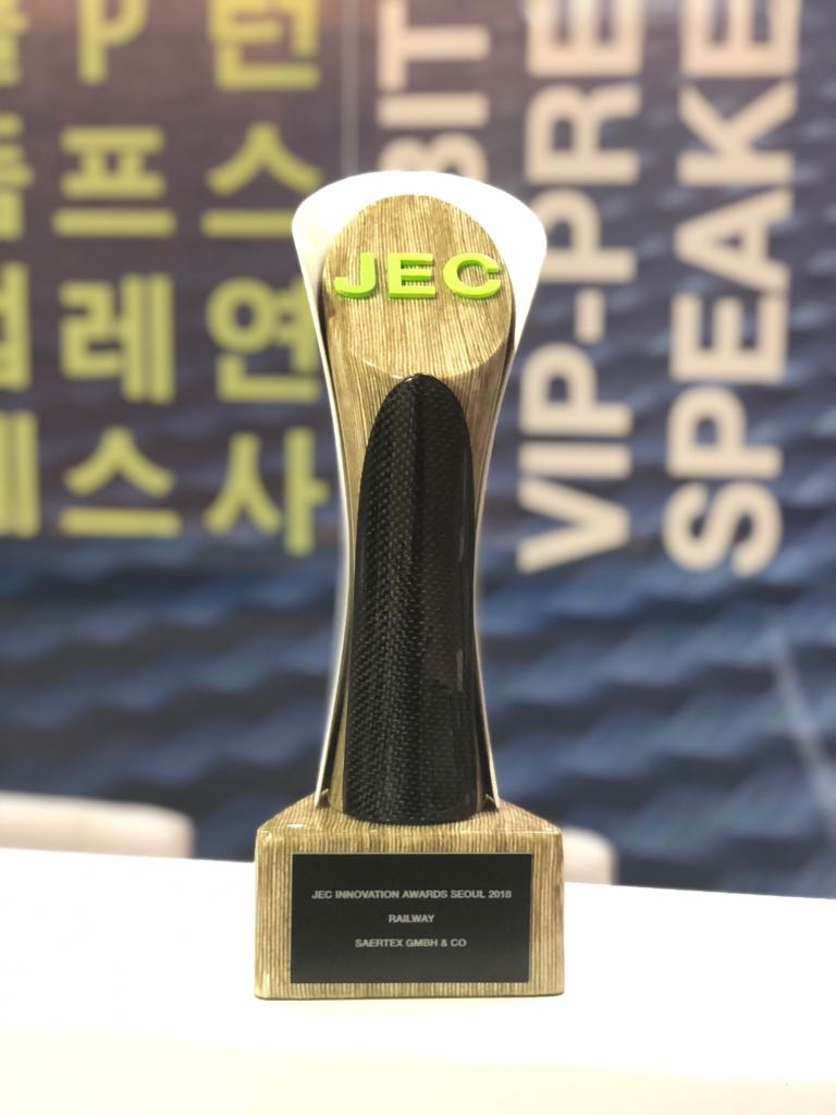 Eine JEC-Innovation-Award-Trophäe steht vor einem unscharfen Hintergrund mit koreanischer und englischer Beschriftung.