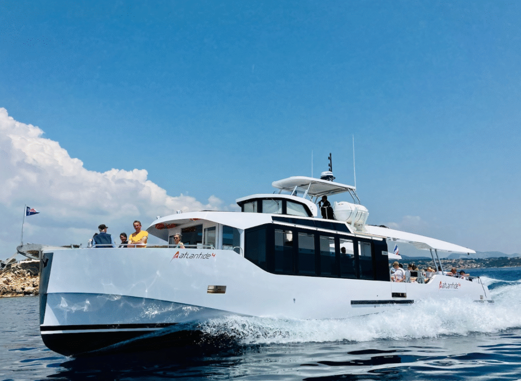 Ein modernes weißes Motorboot fährt bei blauem Himmel über das Wasser und erzeugt Bugwellen.