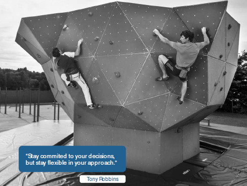 Zwei Männer klettern an einer großen, geometrischen Outdoor-Boulderwand.