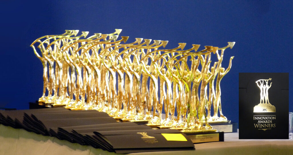 Mehrere goldene Trophäen und dunkle Urkunden auf einem Tisch, daneben ein Schild mit der Aufschrift „Innovation Awards Winners“.