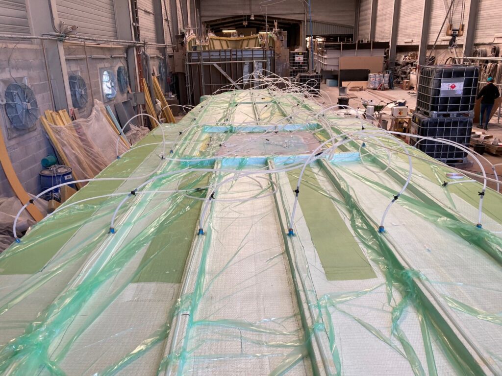 Ein großes, mit grünem Kunststoff und Schläuchen bedecktes Bauteil in einer Industriehalle.