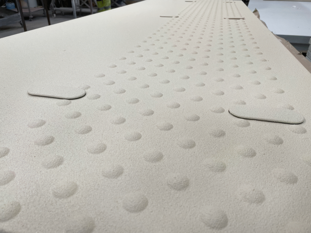 Große helle Platte mit regelmäßigem Noppenmuster in einer Werkstatt oder auf einer Baustelle.