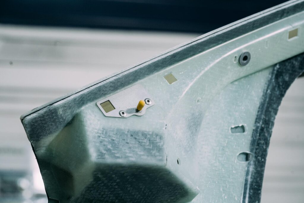 Nahaufnahme eines metallischen Fahrzeugteils mit Bohrungen und Befestigungselementen