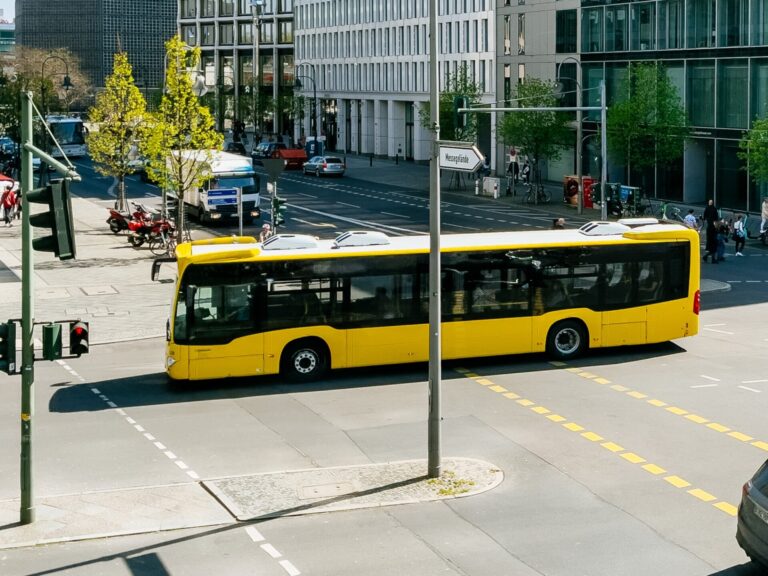 A yellow bus drives past a road junction.