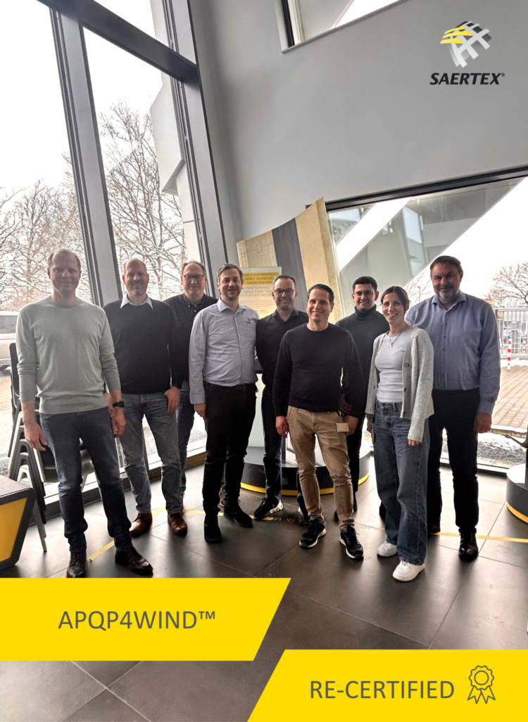 Eight people are standing in a modern interior in front of a Saertox logo; at the bottom of the image are the words „APQP4WIND™“ and „RE-CERTIFIED.“.