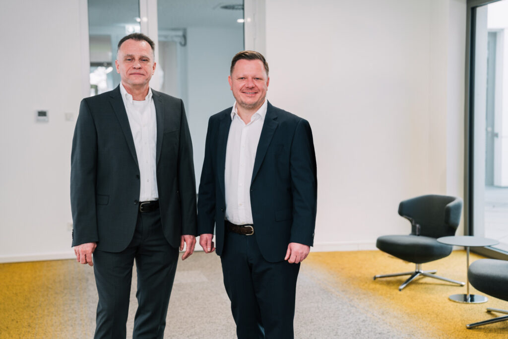 Two men in suits stand in an office