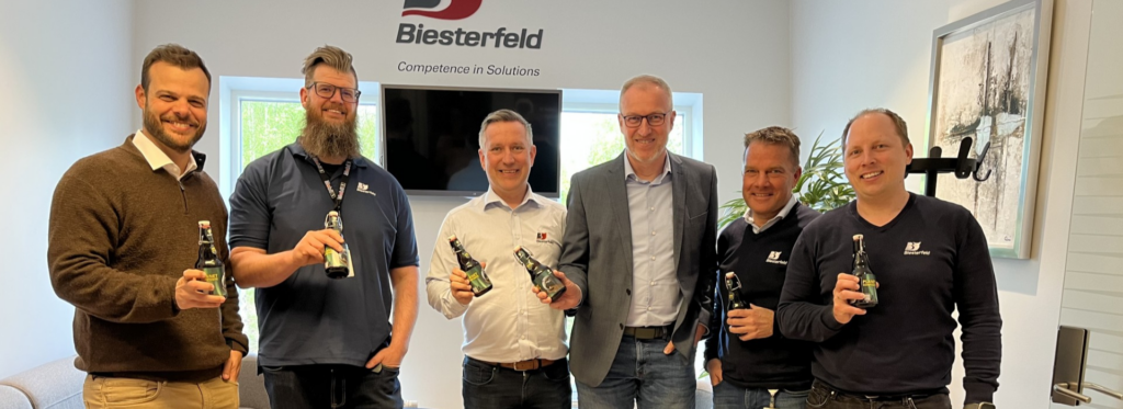 A group of people in an office holding beer bottles.